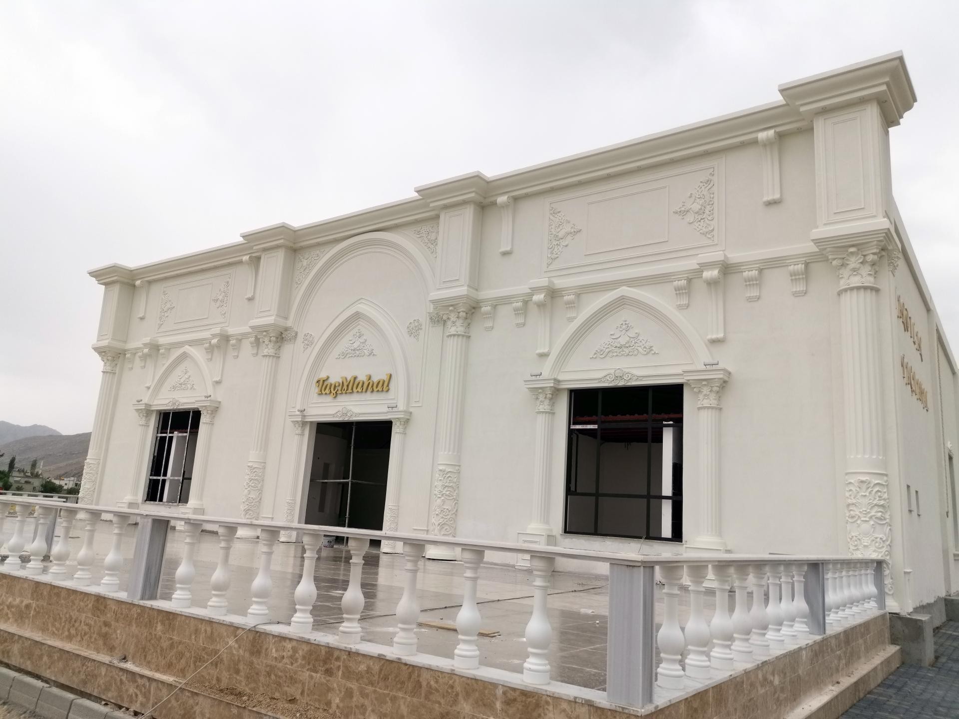 Klasik korkuluklu bir terasın arkasında yükselen, poliüretan pilaster sütunlar, sivri pencere kemerleri ve kabartmalarla dekore edilmiş TaçMahal binası.