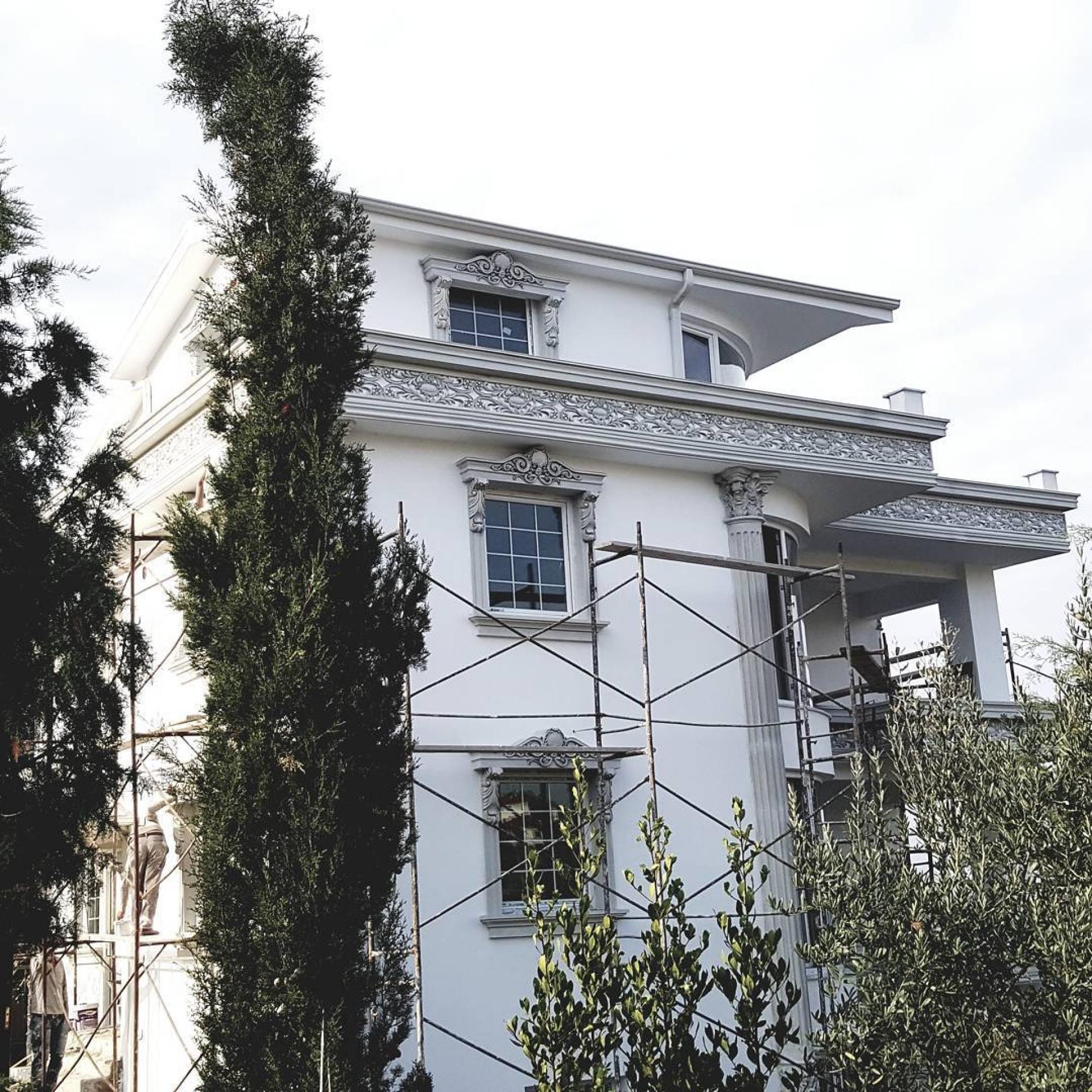 Yapım aşamasındaki bir villanın dış cephesinde iskele yardımıyla kurulan poliüretan pencere taçları, kat arası oymalı frizler ve sütunların görünümü.