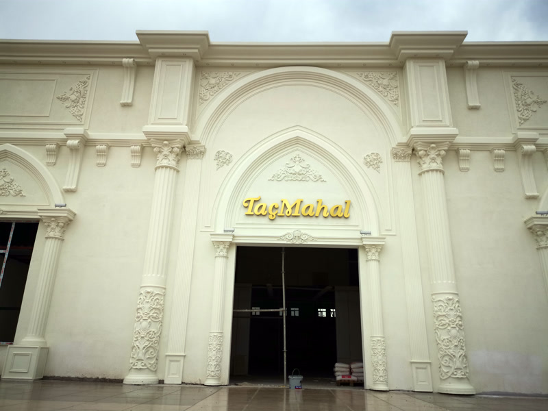 "TaçMahal" yazılı ana girişi bulunan, krem renge boyanmış, poliüretan pilaster sütun, kemer ve kabartmalarla kaplı büyük etkinlik binası cephesi.