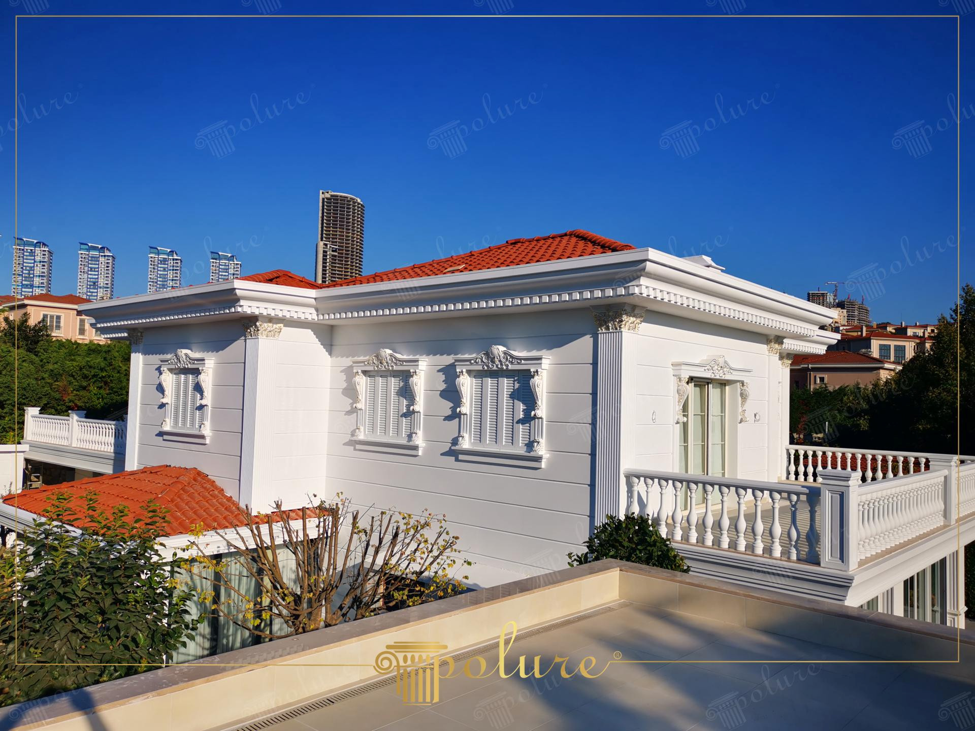 Beyaz renkli dış cephesinde yatay paneller, pencere söveleri, pilaster sütunlar ve teras korkulukları uygulanan kırmızı çatılı klasik lüks villa.