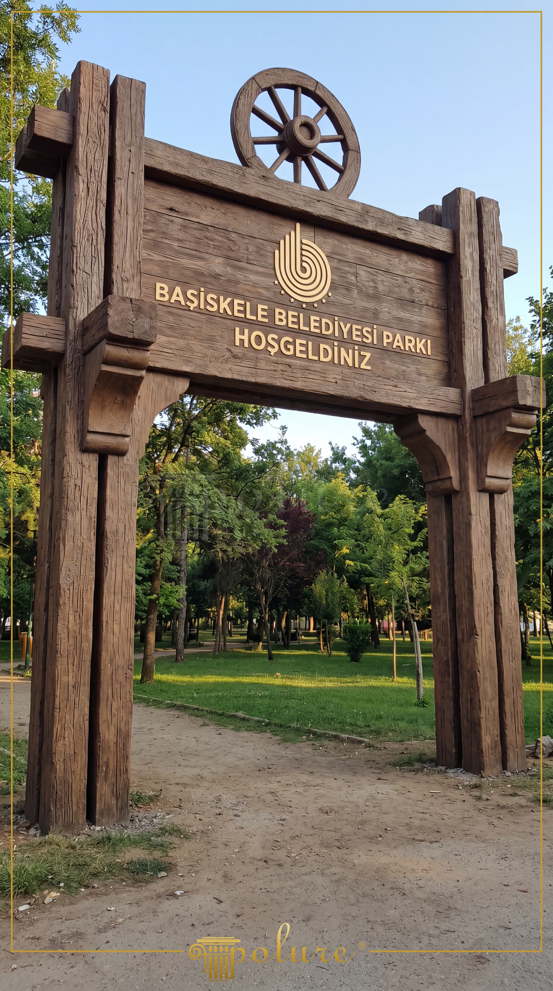 Ağaçlık park girişinde yer alan, üzeri yazılı, tekerlek figürlü büyük boy ahşap görünümlü poliüretan kütük giriş takı.