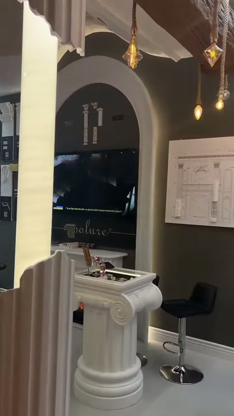 Aydınlatmalı panel yanında antik başlıklı masa ve kemerli duvar düzenlemesi bulunuyor