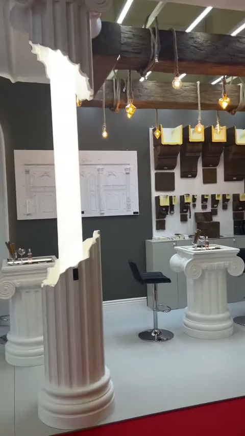 Yivli sütun gövdesi, numune panoları ve dekoratif masa önünde yükseliyor