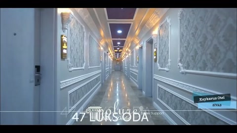 Uzun otel koridorunda duvar çıtaları, aplikler ve tavan ışıkları sıralanıyor
