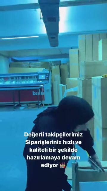 Görevli, makine önündeki çalışma yüzeyinde parçaları kontrol ediyor.