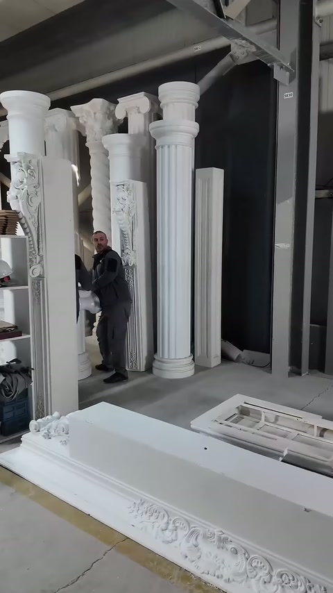 Çalışan, farklı biçimlerdeki beyaz sütun modelleri arasında duruyor.
