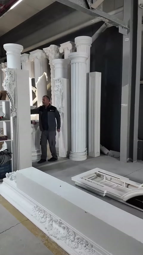 Usta, sergilenen yivli sütunların yanında montaj alanını inceliyor.