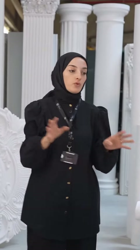 Beyaz dekoratif sütunlar arasında duran sunucu ürünleri karşılaştırarak tanıtıyor