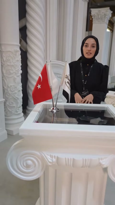 Sunucu geniş volütlü başlığın arkasında elleriyle biçimi açıklıyor