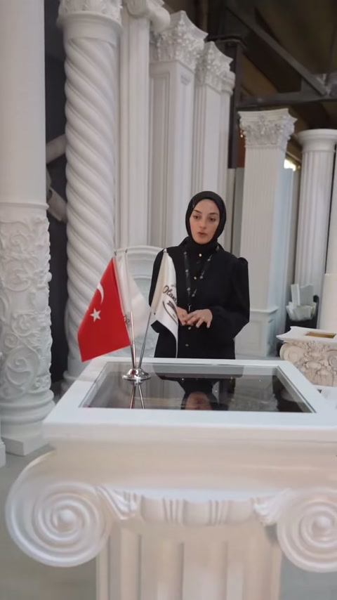 Volütlü başlık önünde duran sunucu dekoratif sütun grubunu anlatıyor