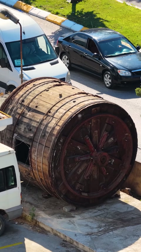 Fıçı biçimli ahşap obje, otopark kenarında üst açıdan görülüyor