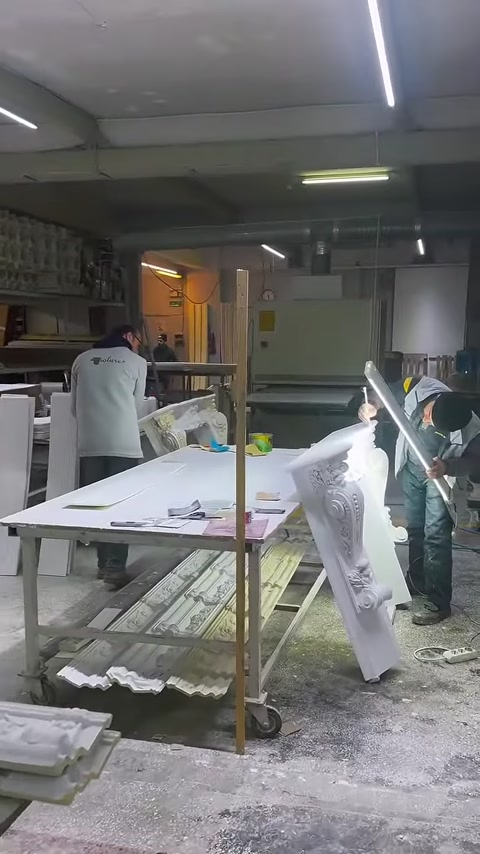 Atölye masasında dekoratif sütun başlıkları ve beyaz profiller görülüyor.
