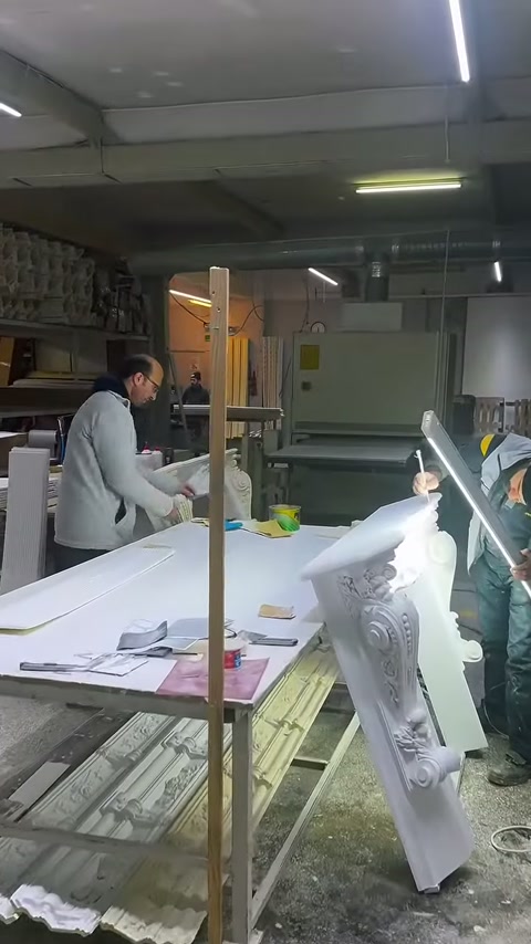 Usta, çalışma masasındaki beyaz sütun başlığını elle inceliyor.