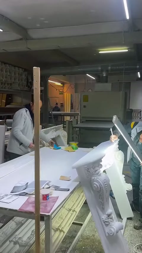 Atölye tezgâhında süslü sütun başlığı ve beyaz levhalar yer alıyor.