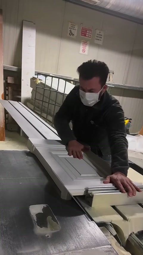Maskeli çalışan, uzun profilleri kesim kılavuzuna bastırarak ilerletiyor.