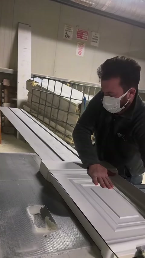 Çalışan, geniş dekoratif parçayı makine tablası boyunca ileri taşıyor.