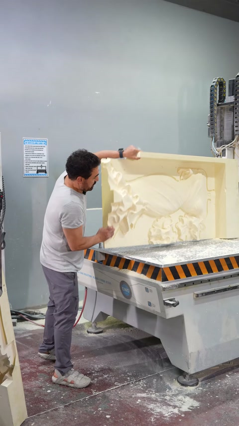 Usta, CNC tezgâhındaki büyük rölyef kalıbının yüzeyini kontrol ediyor.