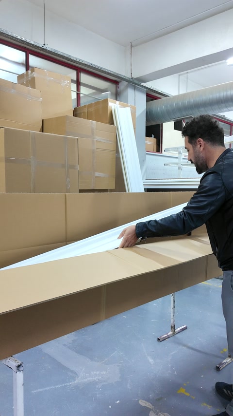 Çalışan, uzun dekoratif profili paketleme kutusuna dikkatlice indiriyor