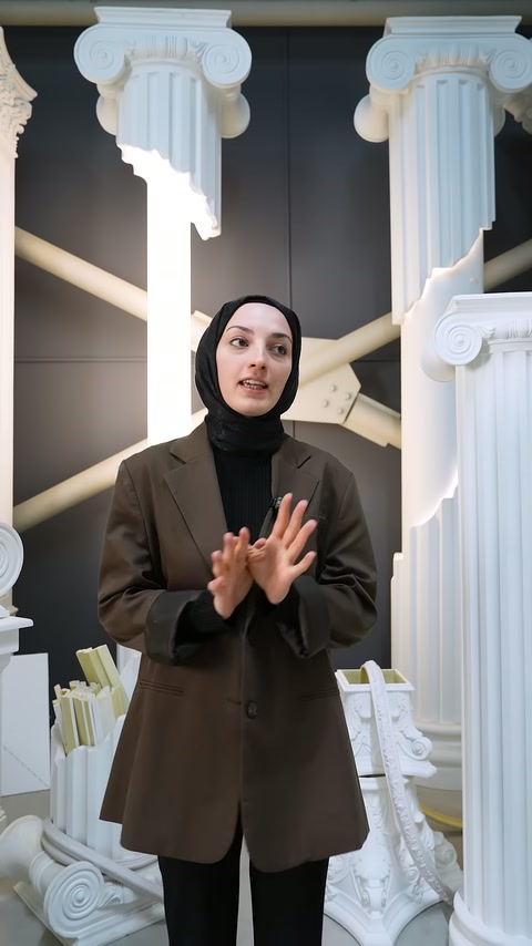 Showroomda kahverengi ceketli sunucu izleyicileri selamlayarak videoyu başlatıyor