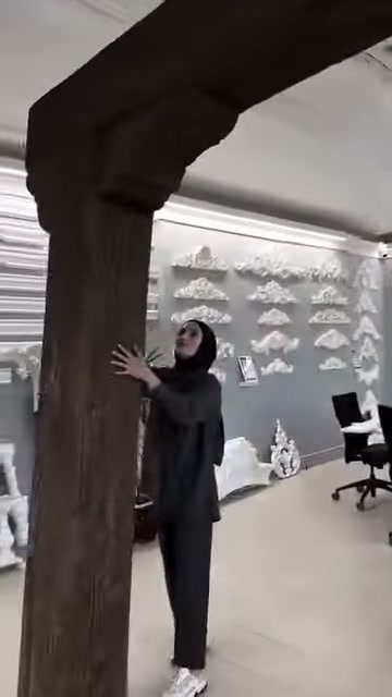 Görevli kalın dikmenin ahşap benzeri yüzeyine iki eliyle dokunuyor