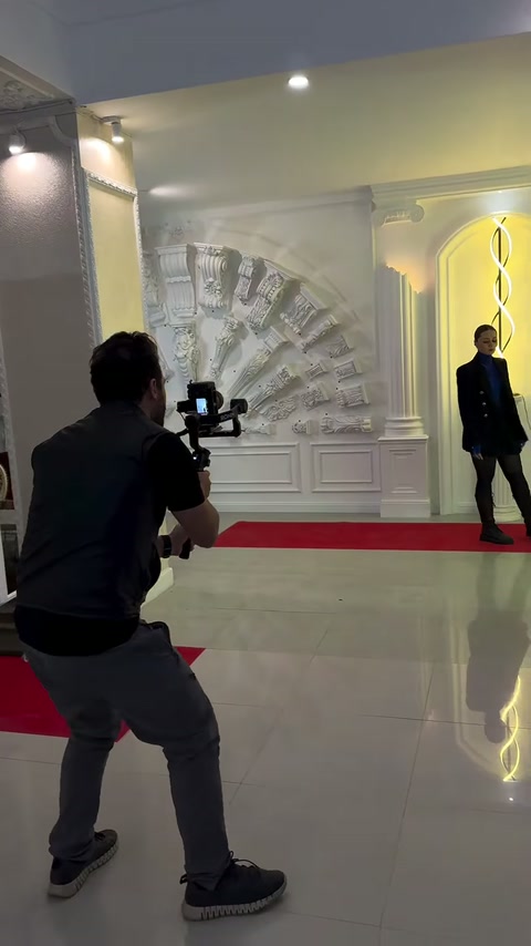 Kırmızı halılı sergi alanında sunucu ve kameraman çekim gerçekleştiriyor
