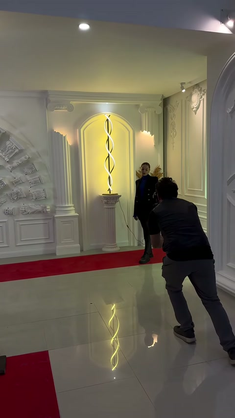Kameraman, ışıklı niş önündeki sunucuyu geniş açıyla kaydediyor