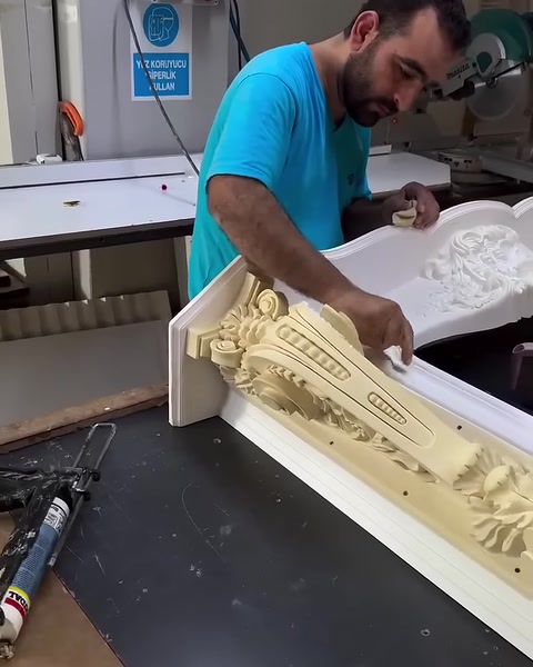 Tezgâhtaki aletler yanında süslemeli şömine çerçevesi üzerinde çalışılıyor.