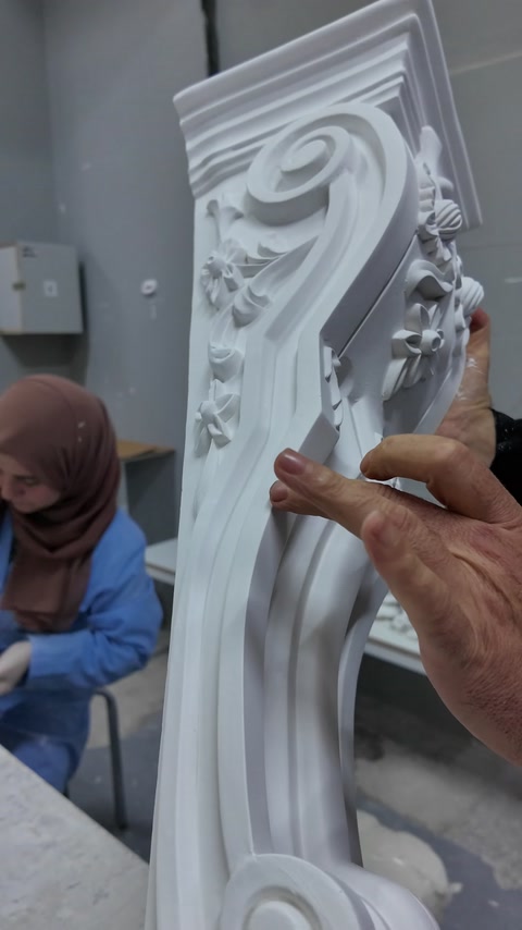 Uzun dekoratif konsolun kıvrımlı kabartmaları ve kenar profilleri inceleniyor