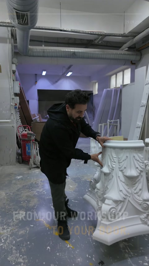 Usta, atölyede beyaz Korint sütun başlığının yüzeyini kontrol ediyor.