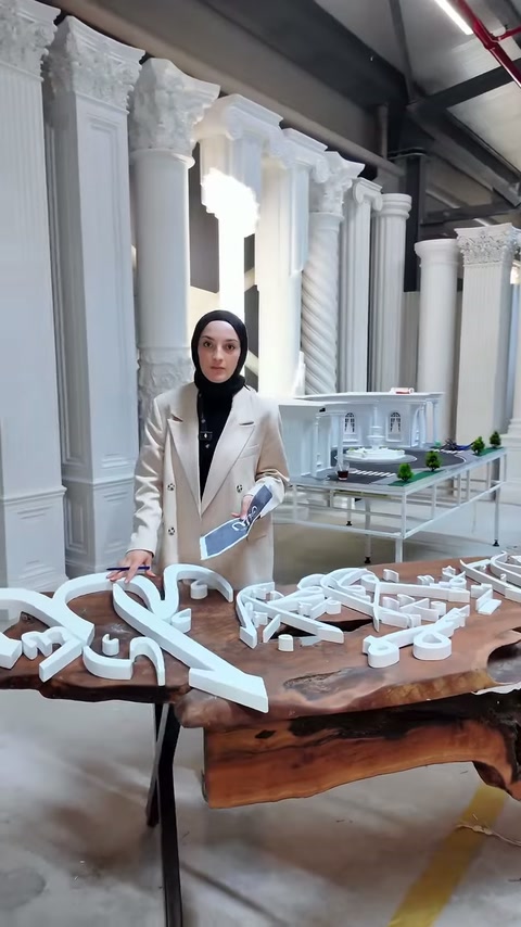 Beyaz tabela harfleri, dekoratif sütunların önündeki masada inceleniyor.