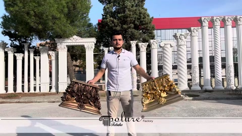 Görevli bronz tonlu ve yaldızlı iki dekoratif başlığı birlikte tutuyor