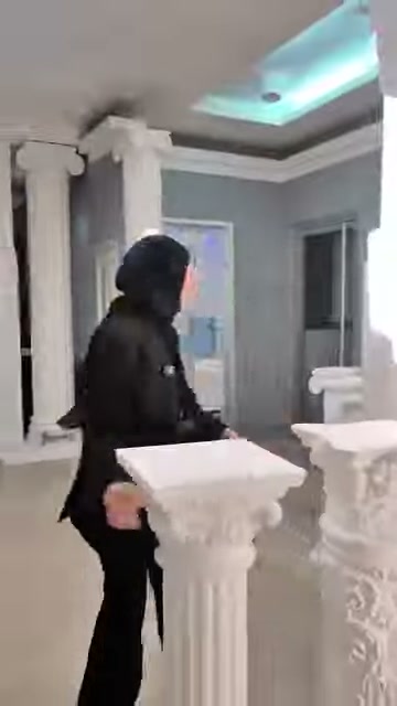 Showroomdaki kıvrımlı ayaklı beyaz sehpa, sunucu eşliğinde tanıtılıyor.
