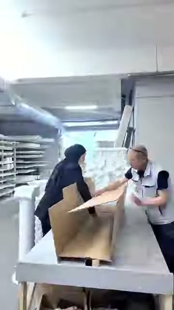 Sunucu ve çalışan, kutu başında beyaz ürünü paketliyor.