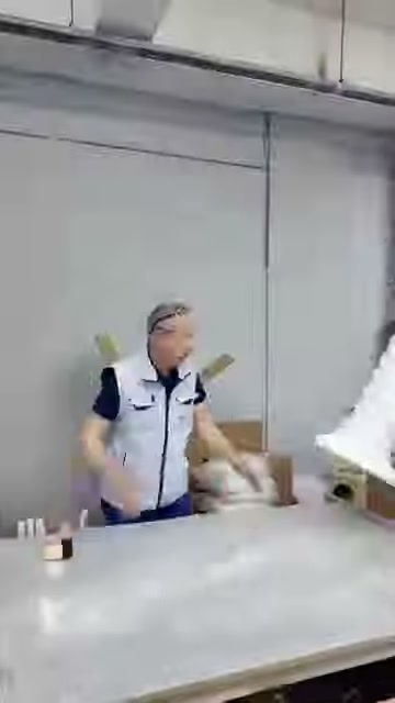 Çalışan, uzun beyaz dekoratif elemanı koruyucu malzemeyle sarıyor.
