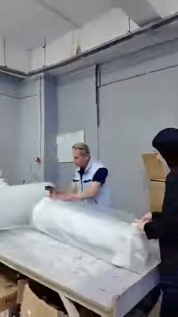 Beyaz dekoratif parça, iki kişi tarafından ambalaj malzemesine sarılıyor.