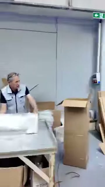 Çalışan, paketlenmiş uzun parçaların yanında açık kutuyla ilgileniyor.