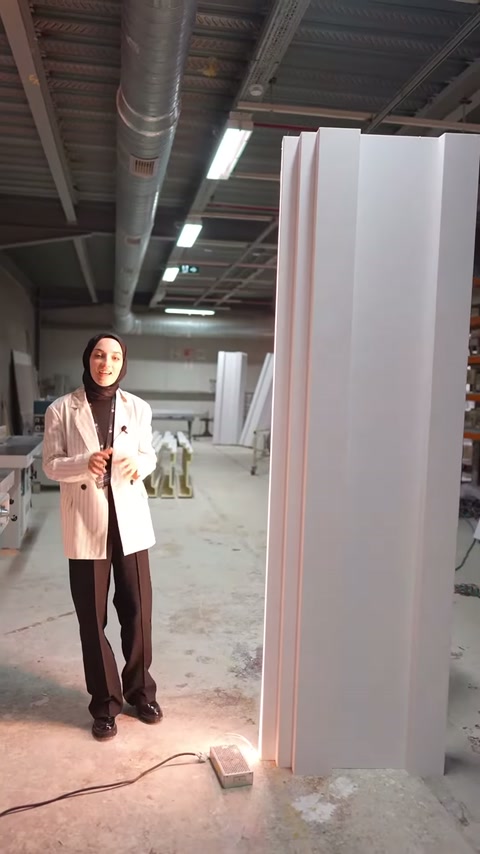 Sunucu, yüksek profillerin yanında durarak dekoratif yüzeyleri tanıtıyor.