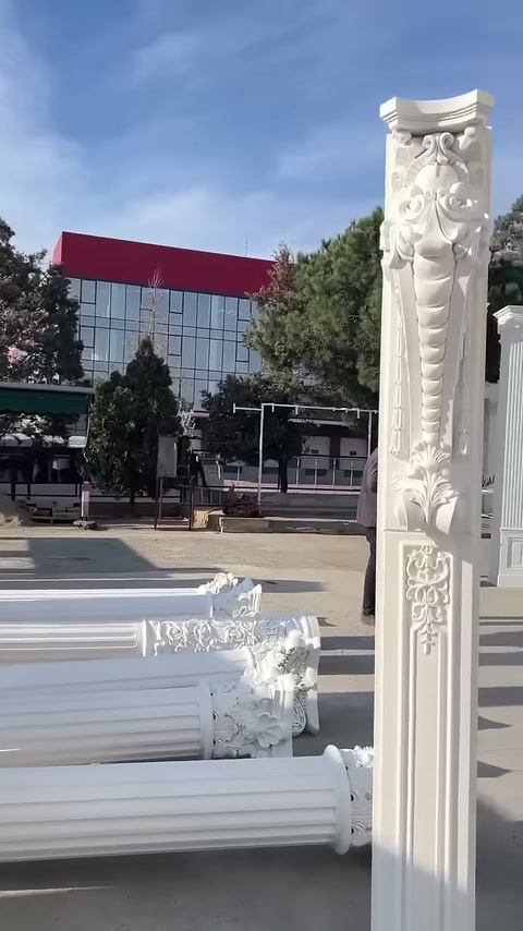Yerdeki yivli sütun gövdeleri, dikey dekoratif parçanın arkasında sıralanıyor