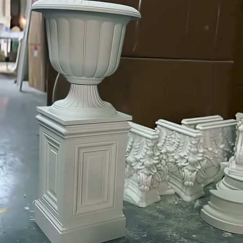 Üretimi tamamlanmış dekoratif saksı, işlemeli parçaların yanında ayakta duruyor.