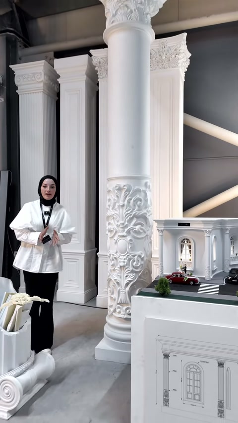 Showroomda sunucu iki yüksek sütun modelinin arasında konumlanıyor.