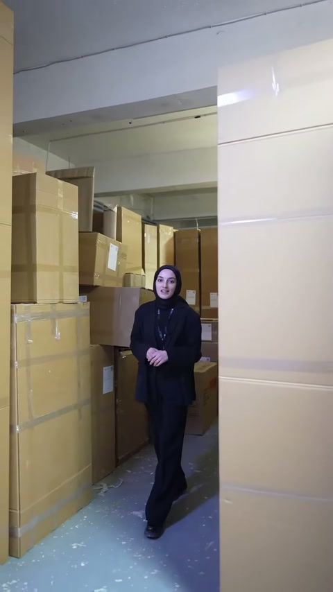 Paketli ürünlerin bulunduğu dar depo yolunda sunum devam ediyor.
