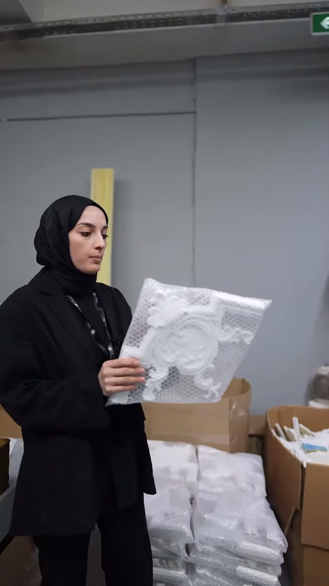 Sunucu, oyma motifli kare parçayı göğüs hizasında tutarak tanıtıyor.