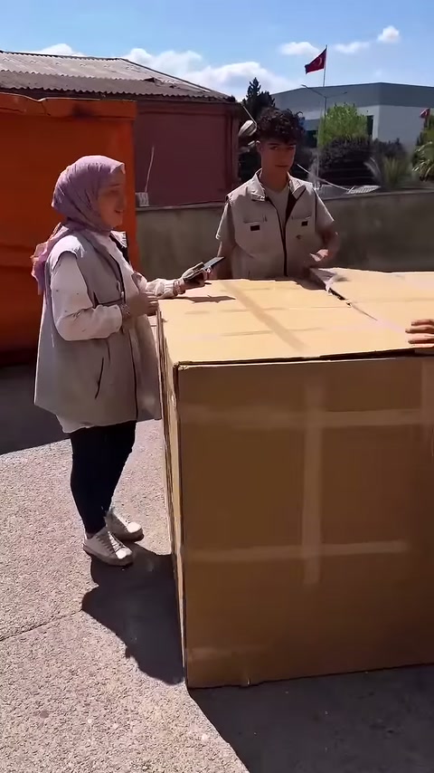 Çalışanlar atölye önündeki büyük karton ambalajın çevresinde hazırlanıyor