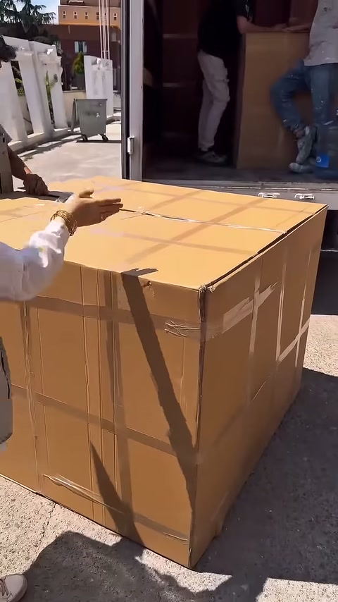 Çalışanlardan biri büyük kolinin üst bölümünü açmaya hazırlanıyor