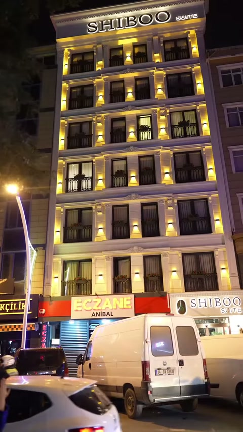Gece çekimi, dekoratif profillerle çevrelenmiş pencere sıralarını cephe boyunca gösteriyor.