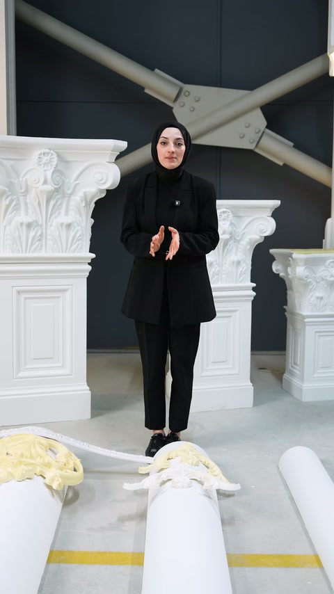 Uygulayıcı tamamlanan kavisli süsleme örneklerinin önünde açıklama yapıyor.