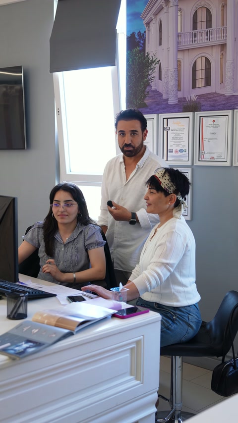 Ayaktaki uzman, oturan tasarımcılara dekorasyon seçenekleri hakkında bilgi veriyor.