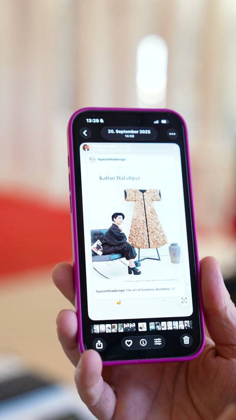 Telefon ekranındaki tasarım gönderisinde oturan kişi ve dekoratif pano görülüyor.
