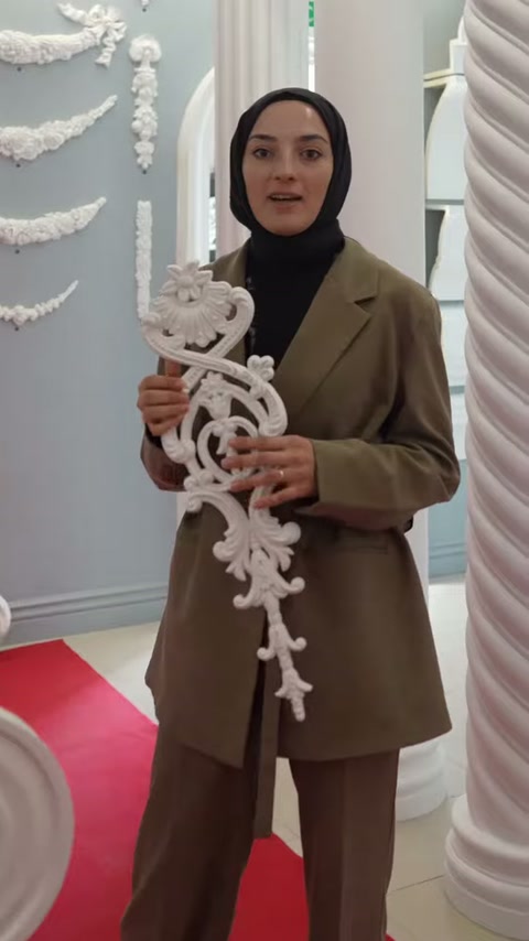 Beyaz dekoratif motif, sütunlu sergi alanında iki elle tanıtılıyor