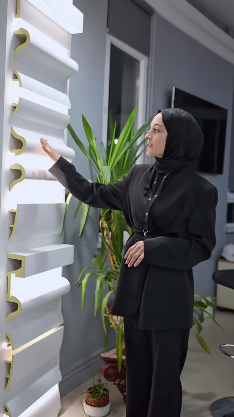 Sunucu showroom duvarındaki gizli ışık kartonpiyer seçeneklerini işaret ediyor.